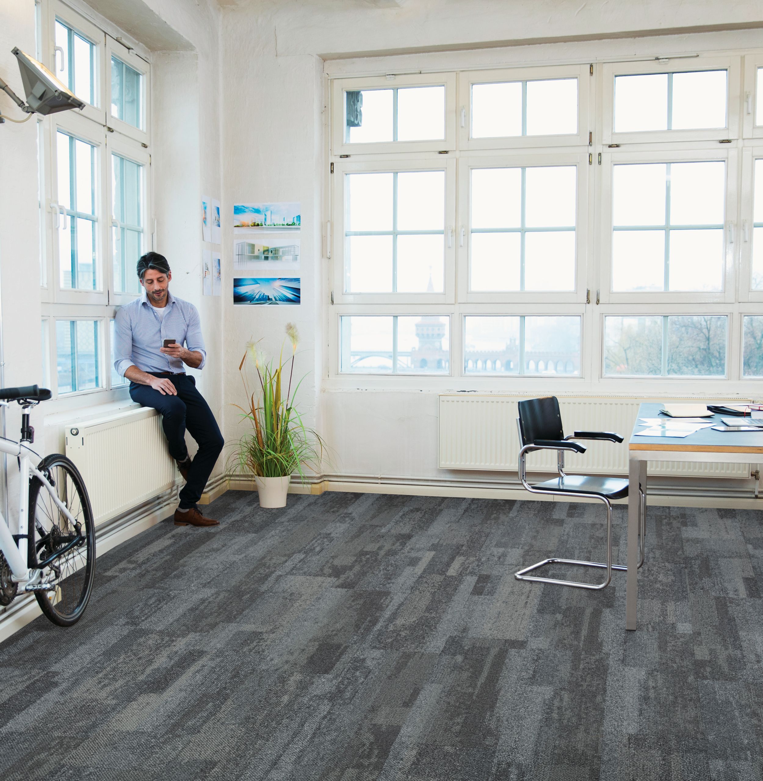Interface Naturally Weathered plank carpet tile in office space with man looking at phone on window sill imagen número 1
